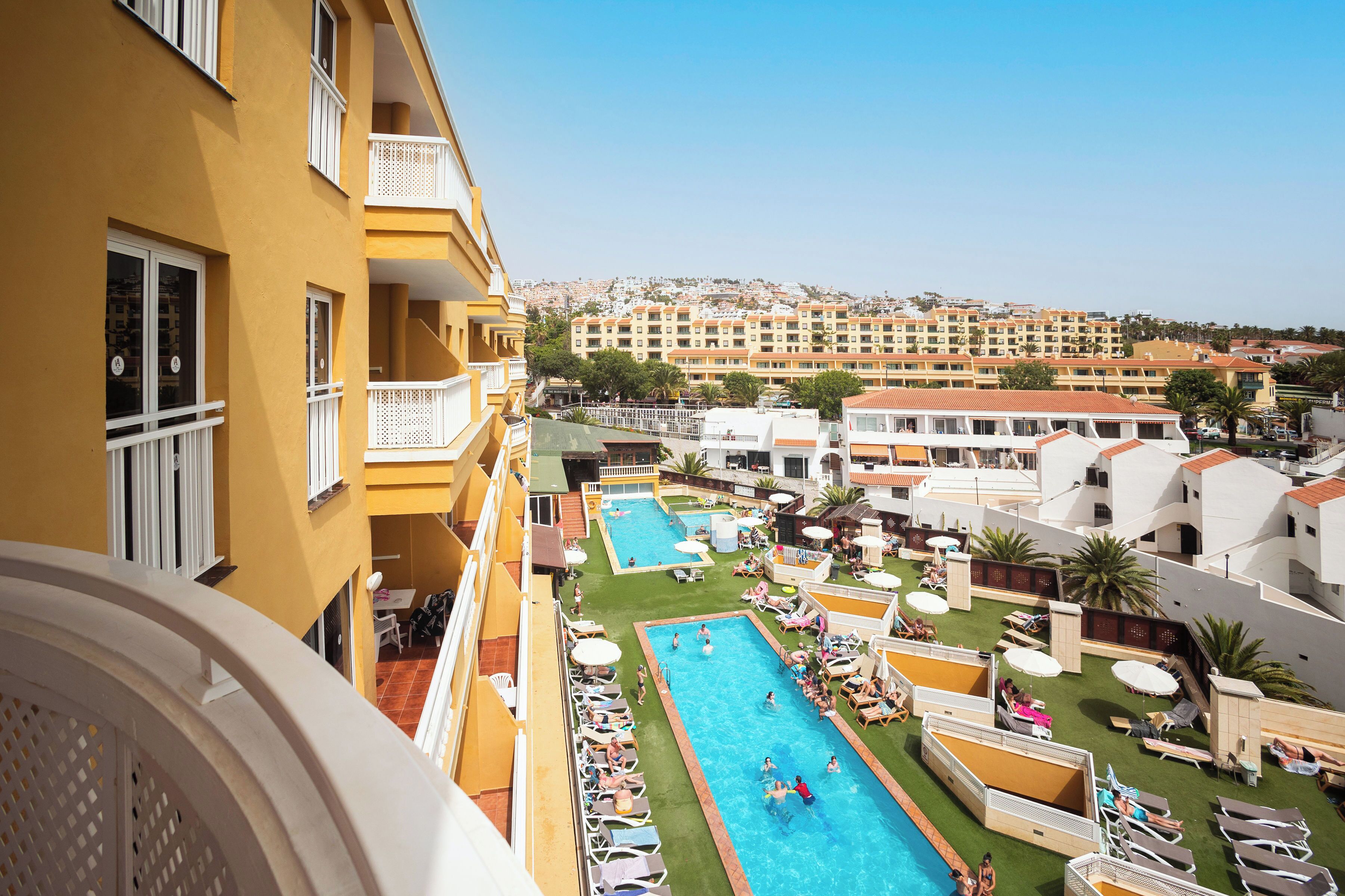 Un hotel con piscina, varios balcones y vistas de los edificios circundantes.
