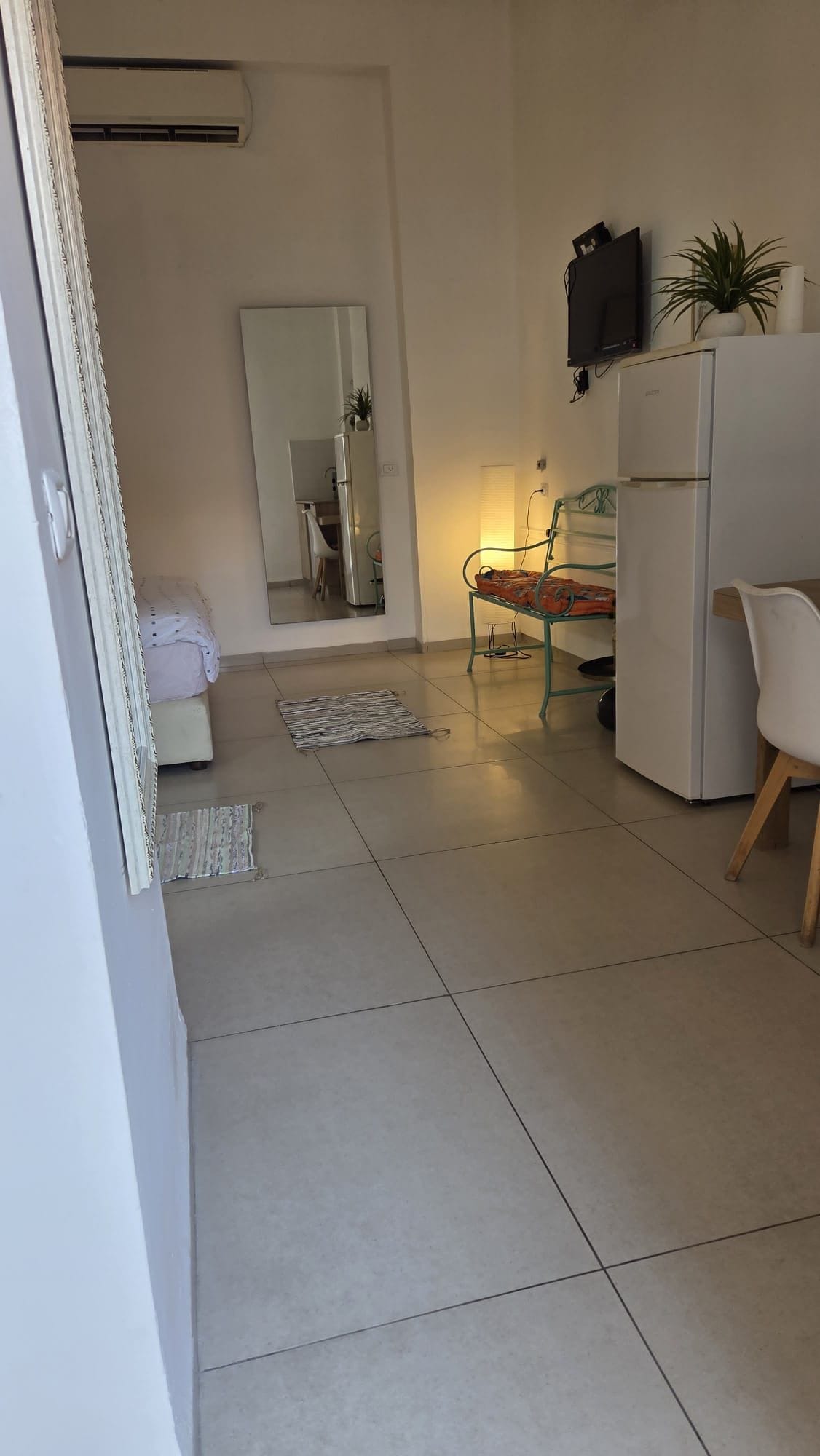 A modern kitchen with white appliances, a dining area with a chair, and a small table.