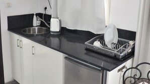 Een kleine keuken met een magnetron, broodrooster en afwasschaal.