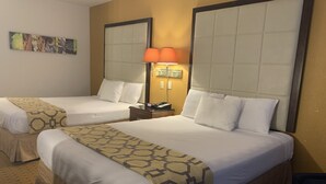 A hotel room with two beds, each with a headboard, a nightstand with a lamp, and a wall-mounted artwork. - Brentwood Inn & Suites (Hobbs)