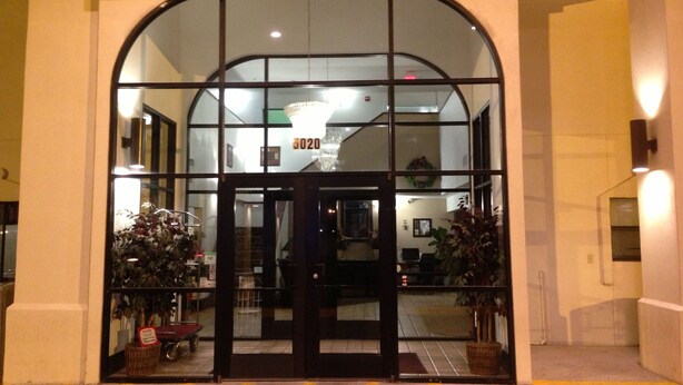 A hotel entrance with a glass door, a number above it, and a staircase leading inside. - Brentwood Inn & Suites (Hobbs)