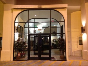 A hotel entrance with a glass door, a number above it, and a staircase leading inside. - Brentwood Inn & Suites (Hobbs)