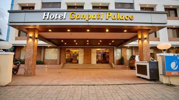 Hotel Ganpati Palace con un vestíbulo cubierto, suelo de baldosas y un letrero.