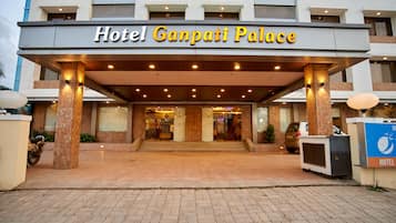 Hotel Ganpati Palace with a covered entrance, tiled flooring, and a signboard.