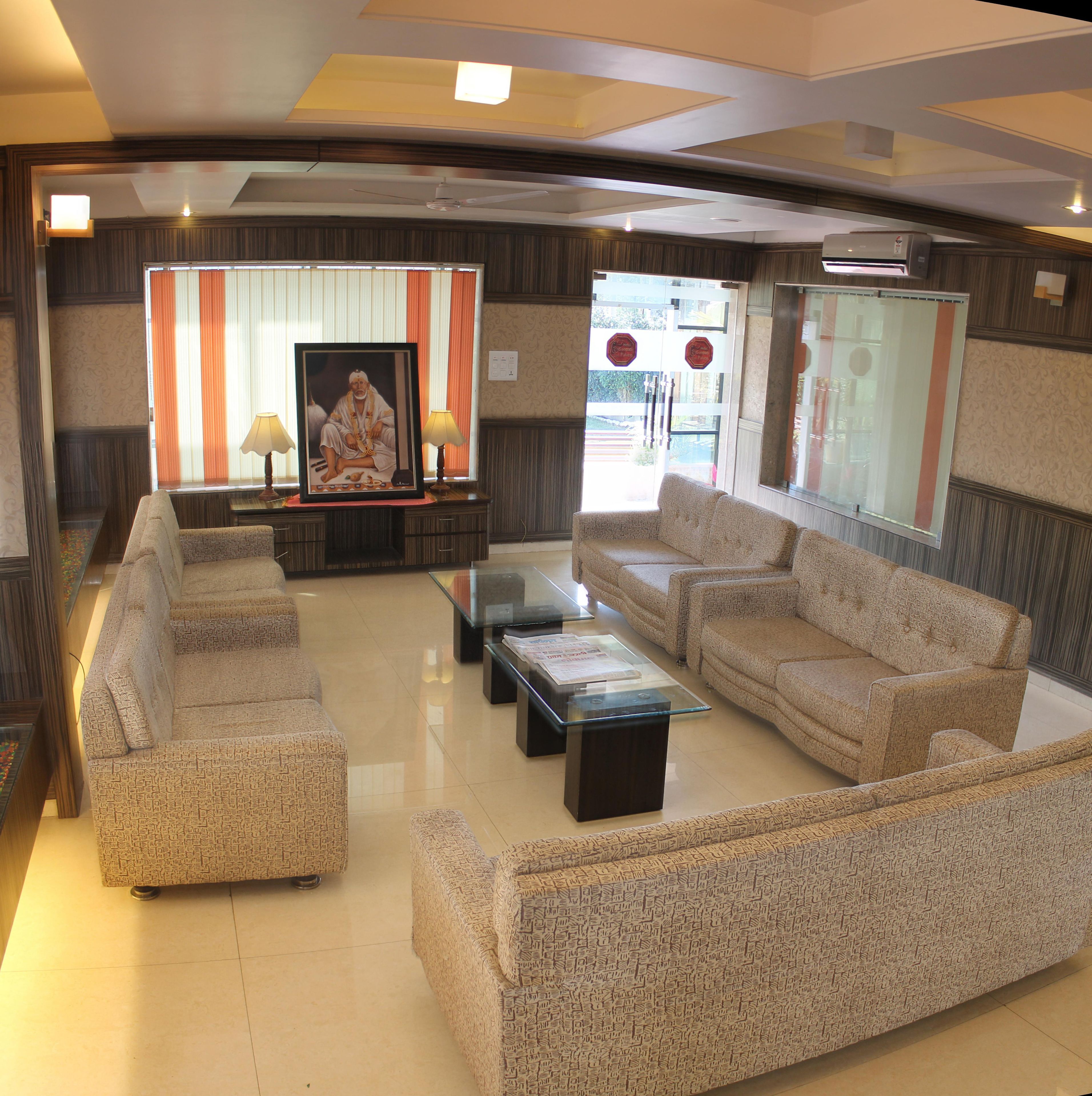A spacious living room with a sofa set, a glass coffee table, and a framed picture on a stand.
