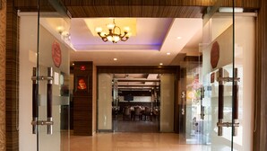 Un vestíbulo de hotel con puertas de vidrio, una araña y suelo de baldosas.