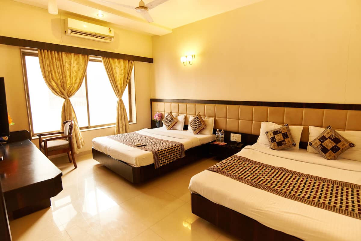 A hotel room with two beds, a desk, a chair, and a TV.