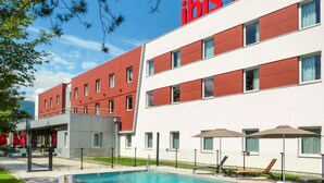 Een hotel met een zwembad, terras en een gevel in rood en wit.
