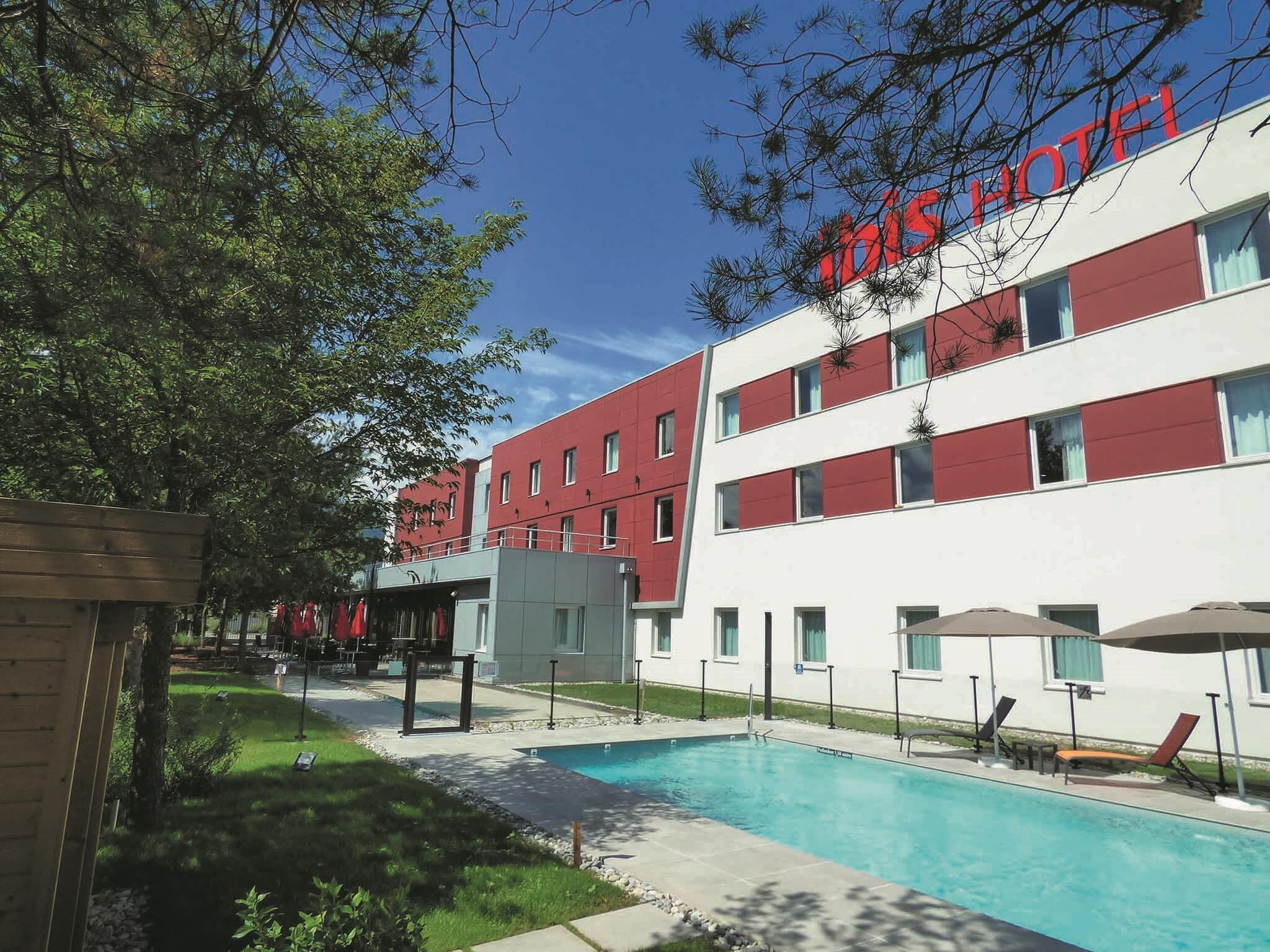 Ein Hotel mit Swimmingpool, Außenbereich und einer roten und weißen Fassade.