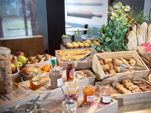 A buffet with various food items, including fruits, pastries, and condiments. - ibis Saint Genis Pouilly Genève (Saint-Genis-Pouilly)