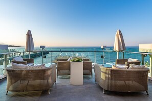 Eine Terrasse mit Korbmöbeln, einem zentralen Tisch und Sonnenschirmen.