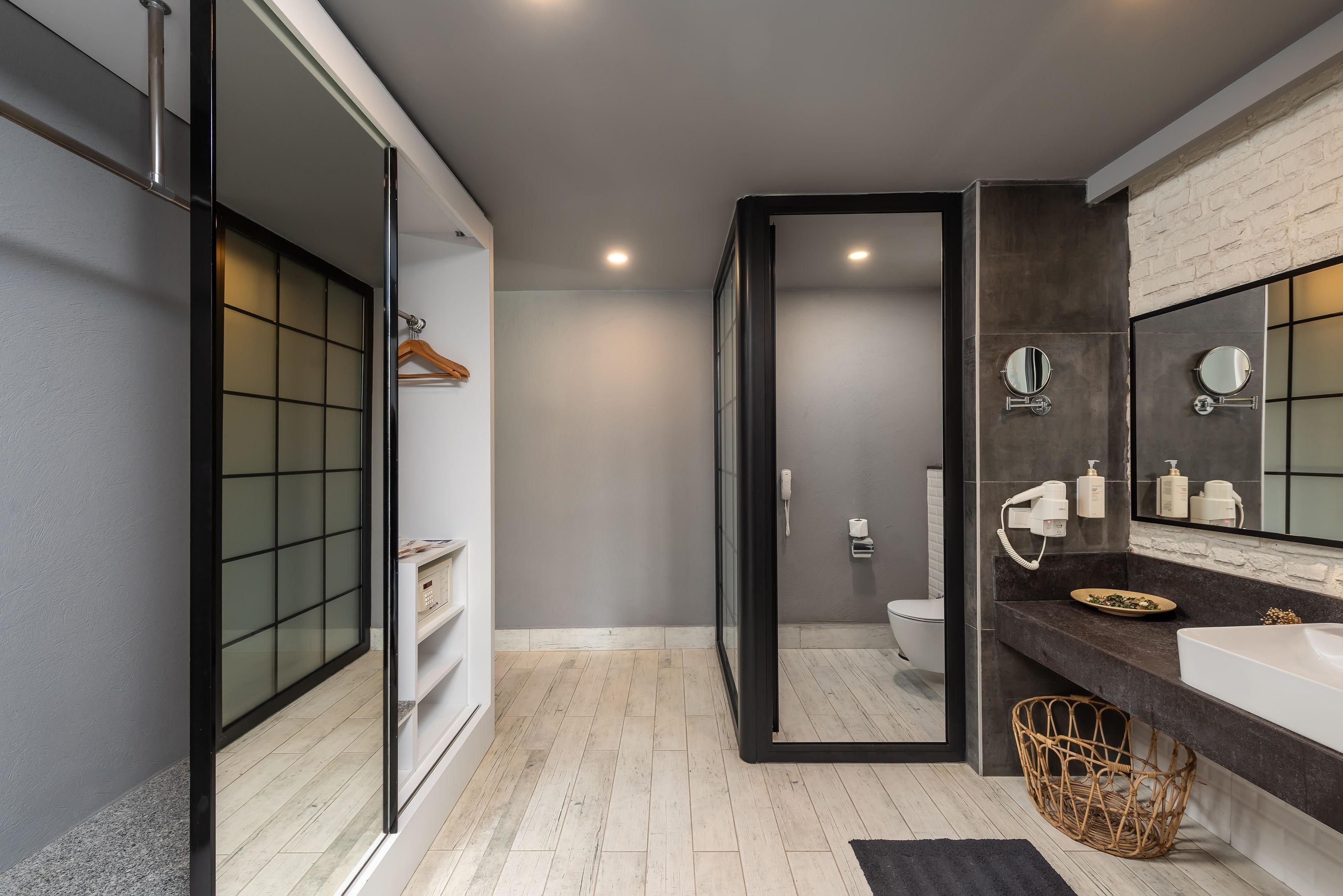 A modern bathroom with a large mirror, a white sink, and a toilet.