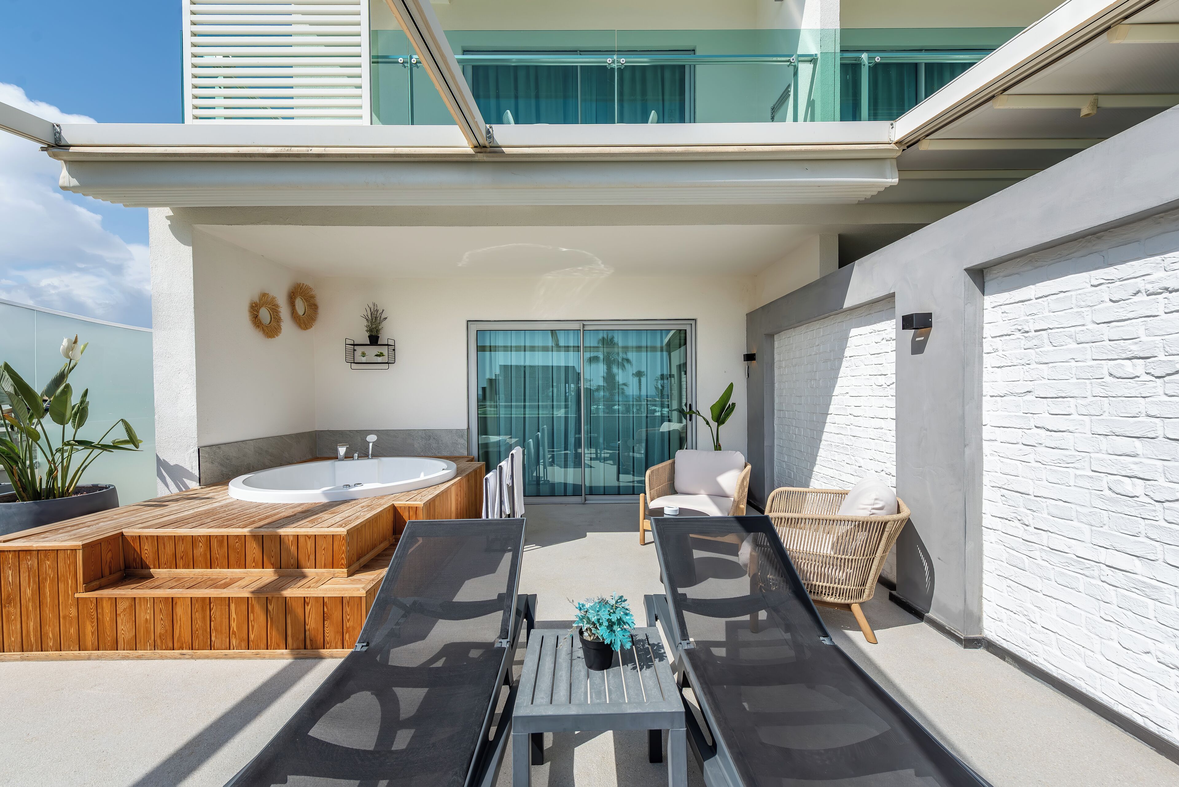 Une terrasse extérieure moderne dotée d’un jacuzzi, de chaises longues et d’un espace salon.