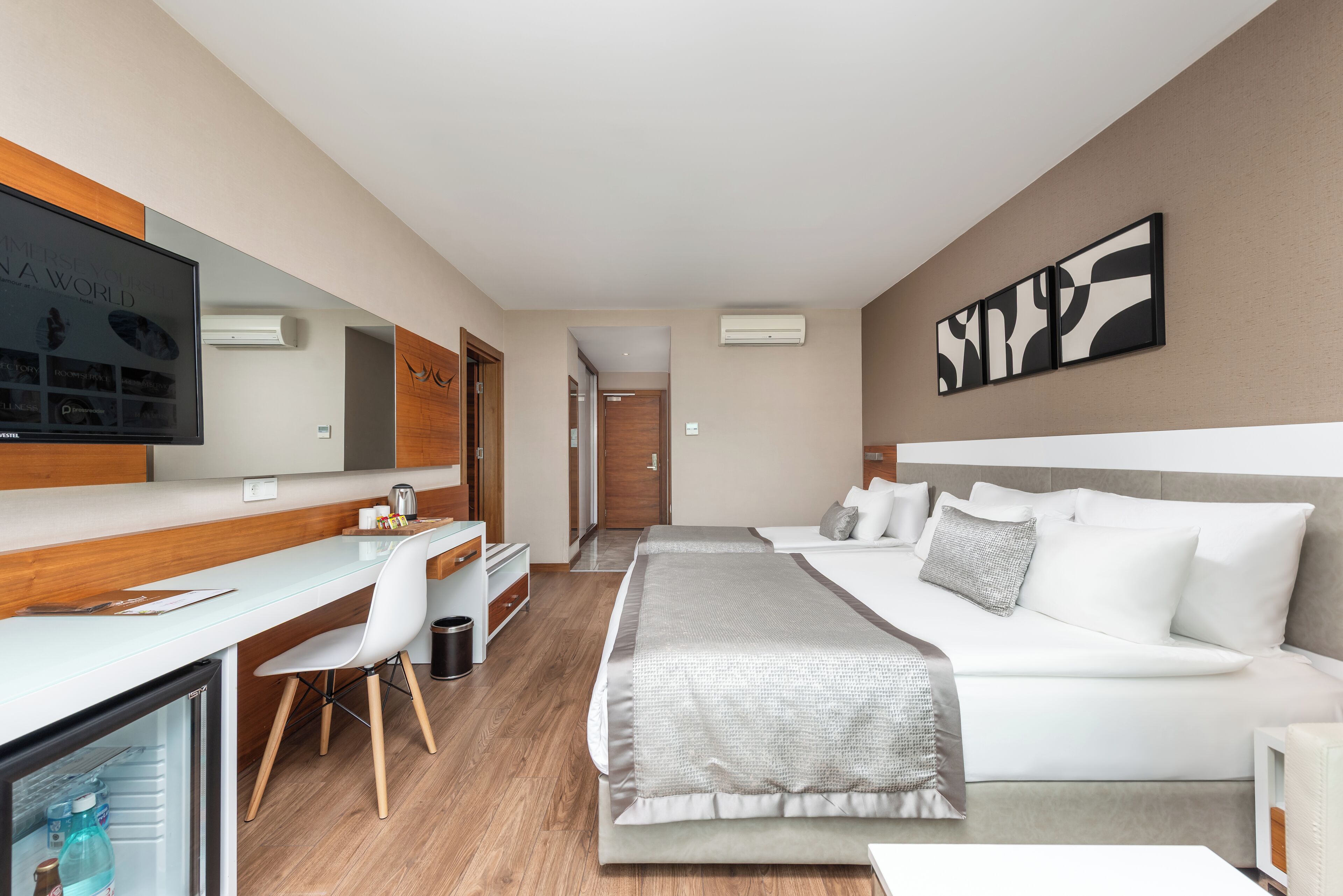 Una camera d'albergo moderna con un letto, una scrivania, una sedia, un televisore e un'opera d'arte appesa al muro.