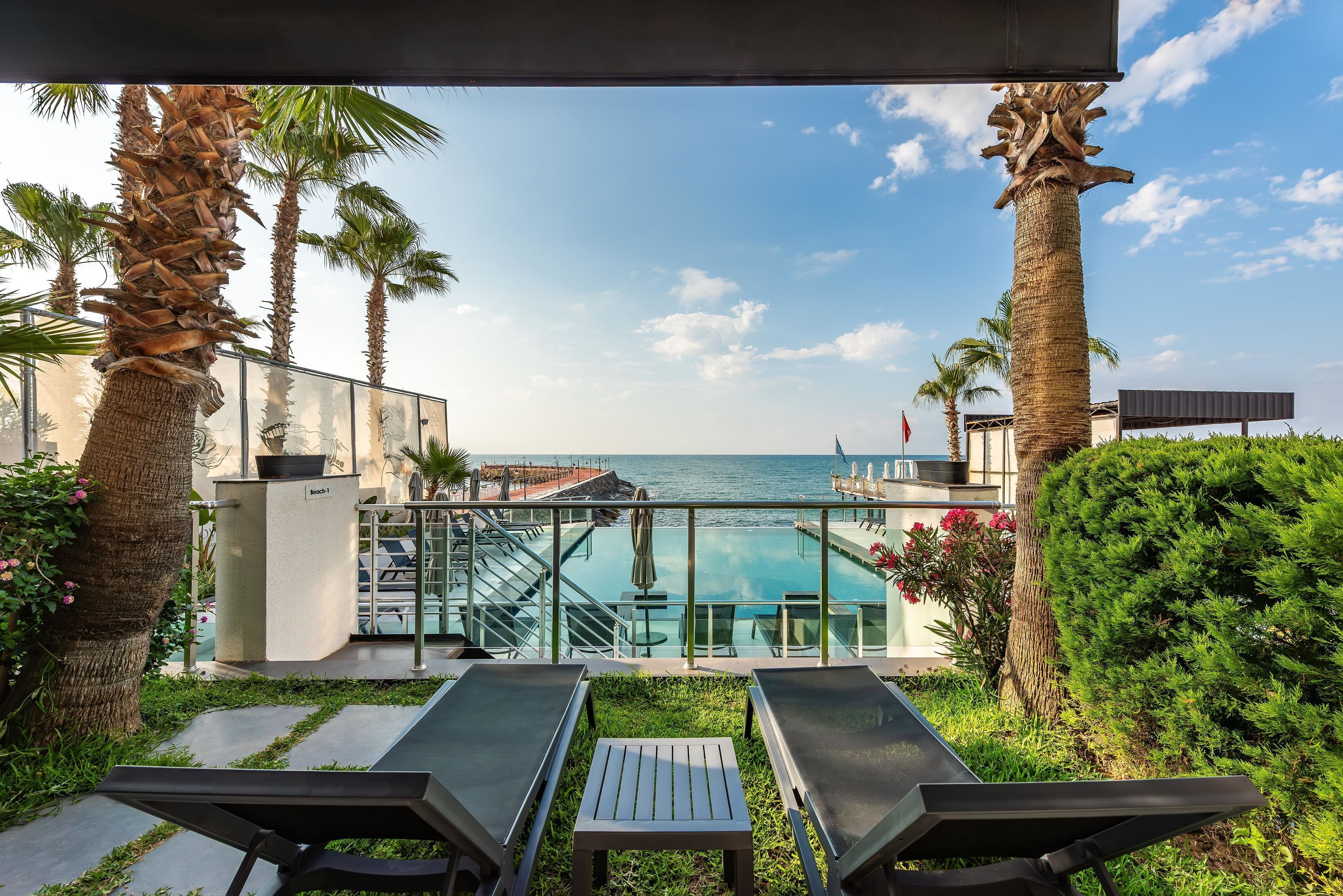 A poolside area with lounge chairs, a small table, and a view of the ocean.