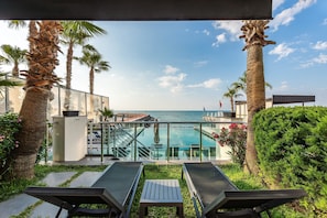 Un espace aménagé au bord de la piscine, avec des chaises longues, une petite table et une vue sur l’océan.