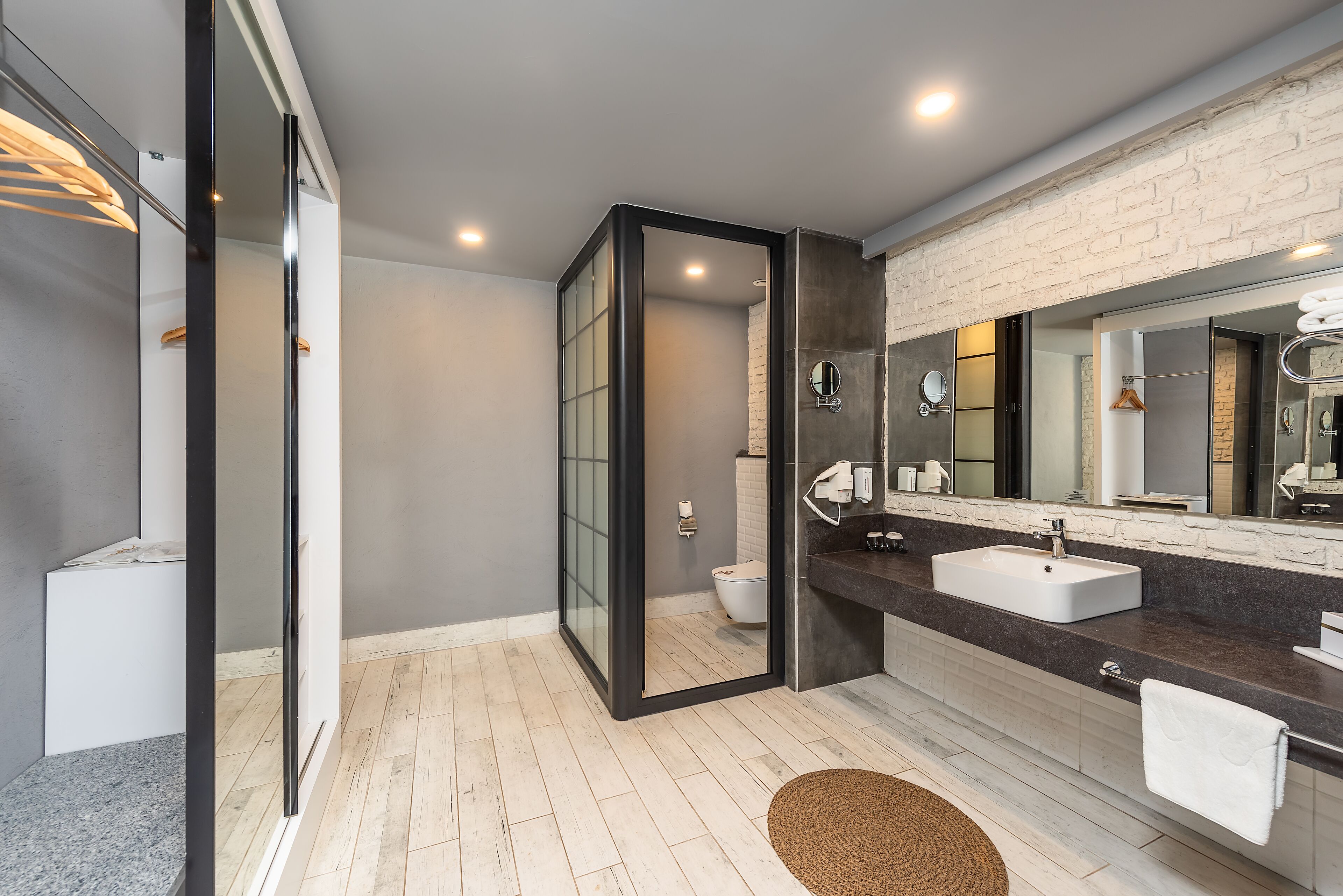 Un baño moderno con cabina de ducha de vidrio, un espejo grande y encimera de granito.