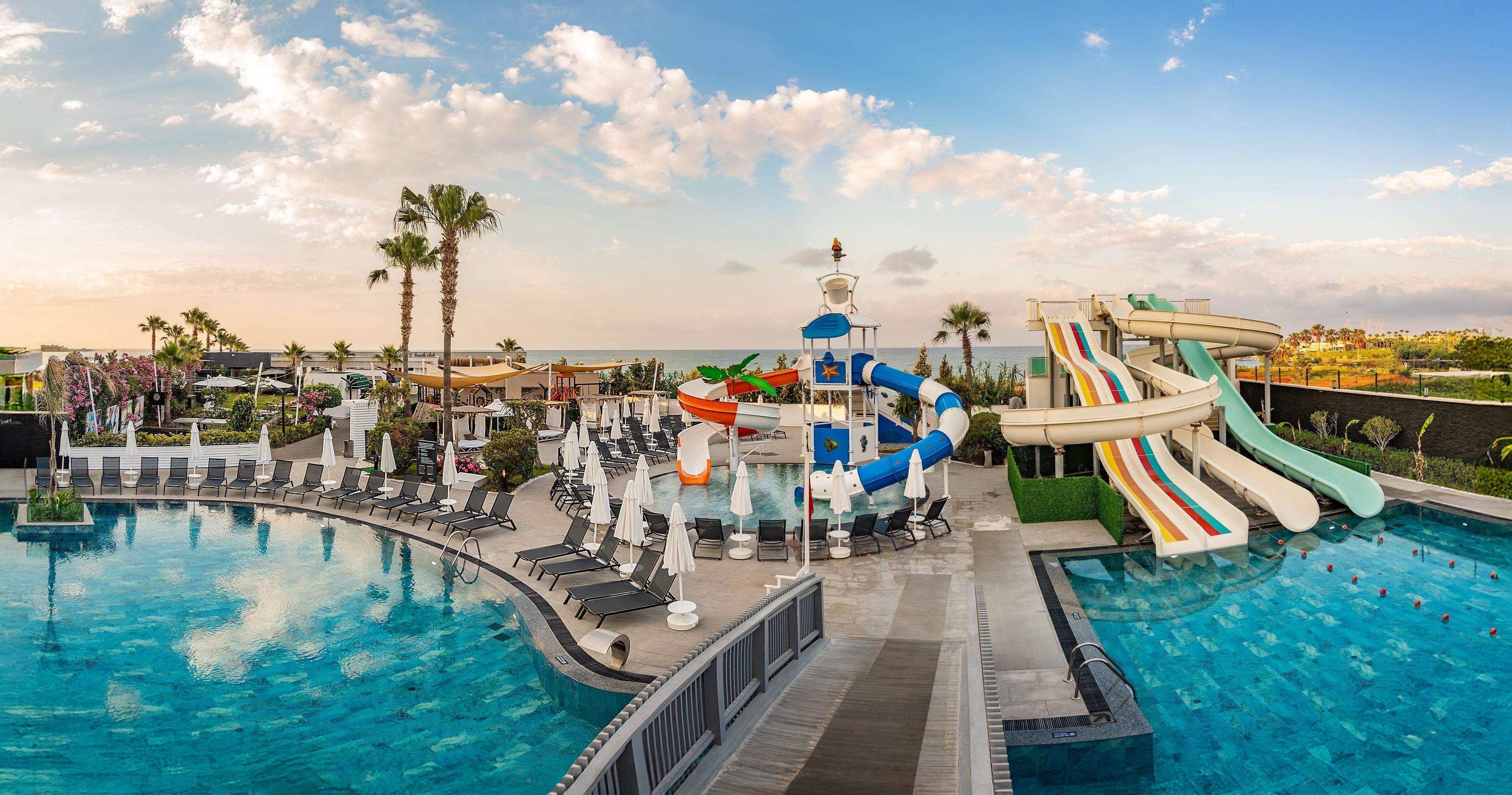 Una piscina de resort con múltiples toboganes y sillones de descanso.