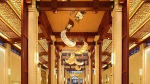 Un hall d’entrée spacieux, doté de hauts plafonds, de poutres en bois décoratives et d’un lustre central.