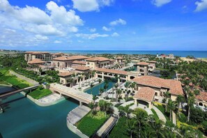 Un resort con varias edificaciones, una piscina central y un puente que conecta diferentes zonas.