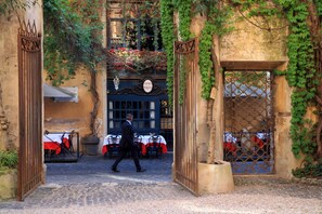 Mukulakivikatu johtaa rakennukseen, jonka julkisivu on sininen ja jossa on kyltti, jossa lukee: ”Osteria Caroni”.