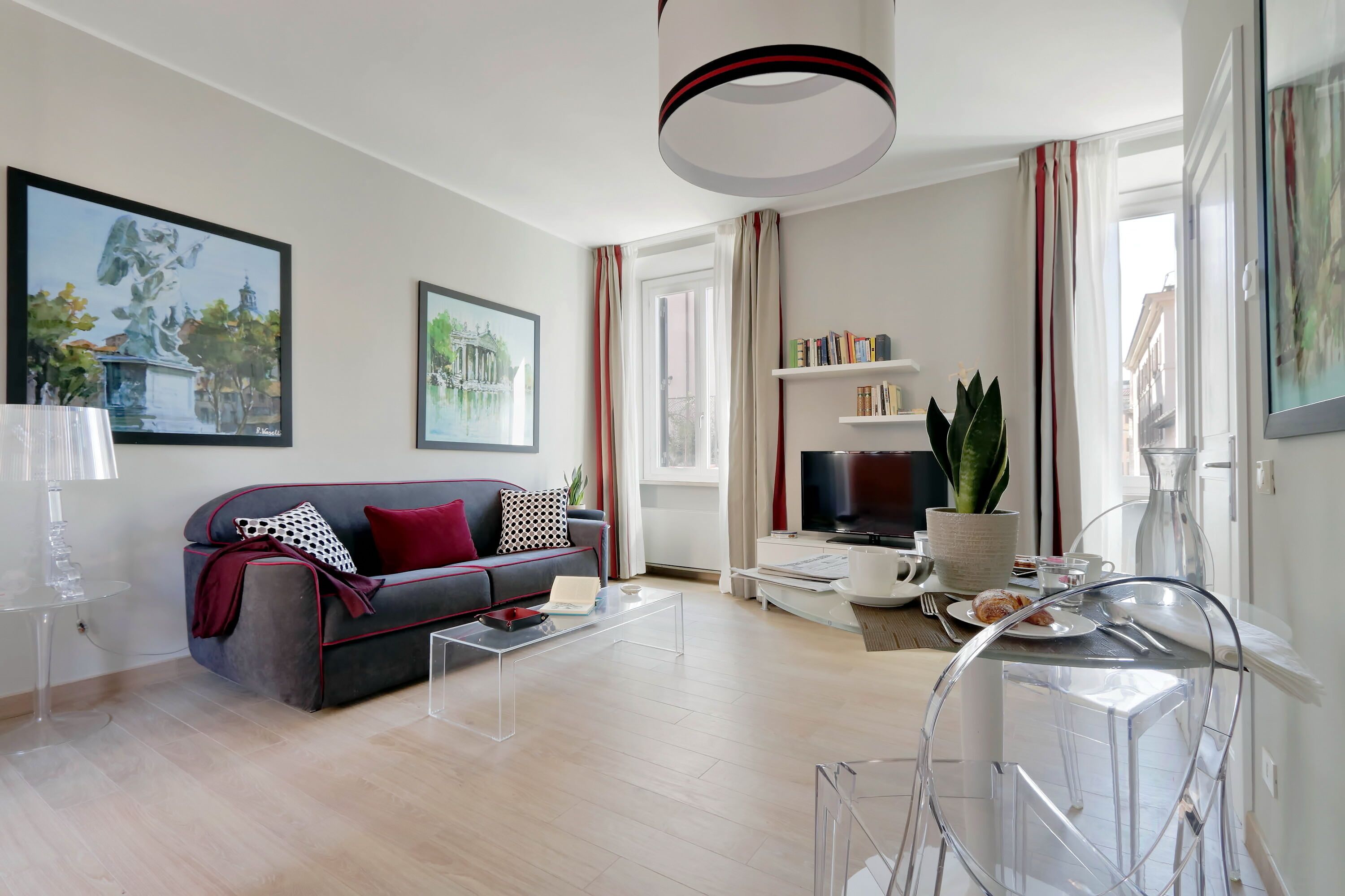 Un salon moderne avec un canapé gris, une table basse, un téléviseur et une bibliothèque.