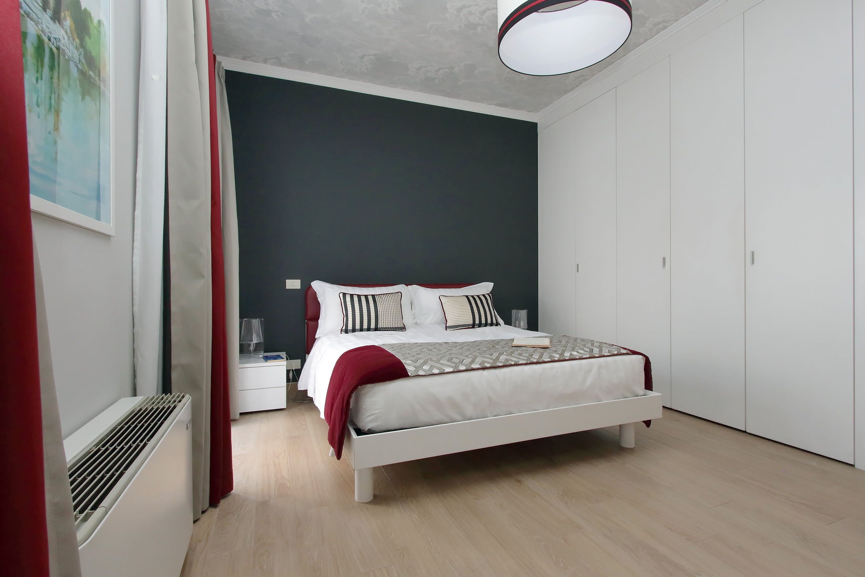 A bedroom with a bed, white wardrobe, and a heater.