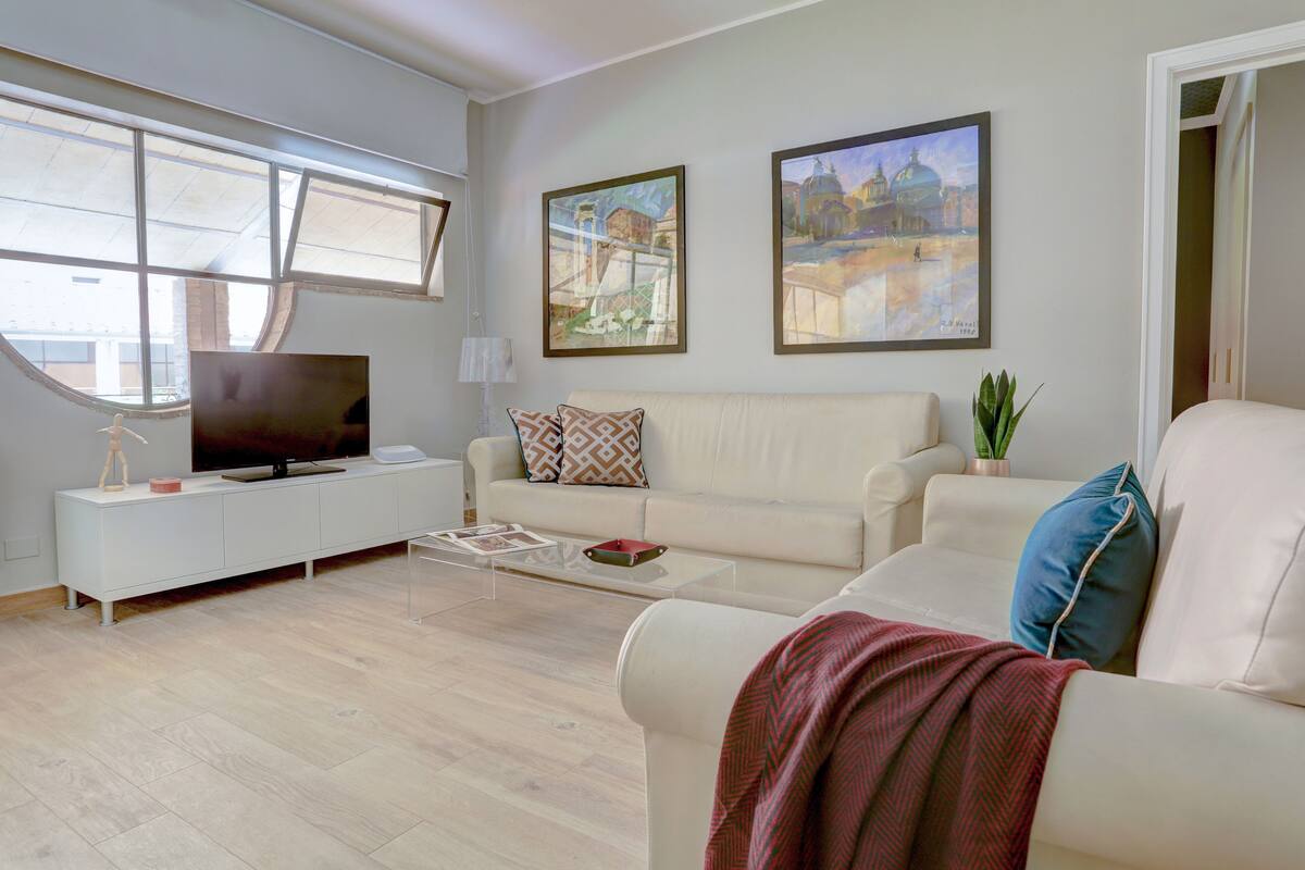 A modern living room with a sofa, coffee table, TV, and artwork on the wall.