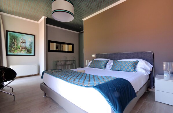 A modern bedroom with a large bed, a bedside table, a chair, and a painting on the wall. - Piazzetta Margutta - My Extra Home (Rome)