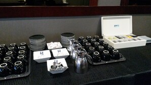A buffet setup with trays of bottles, plates, and a coffee pot. - Résidence d'Artagnan (Montargis)