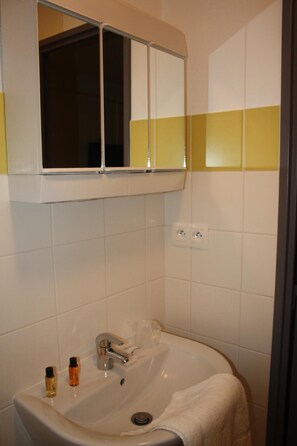 Un baño con un lavamanos blanco, un espejo encima y una toalla colgada en la pared.
