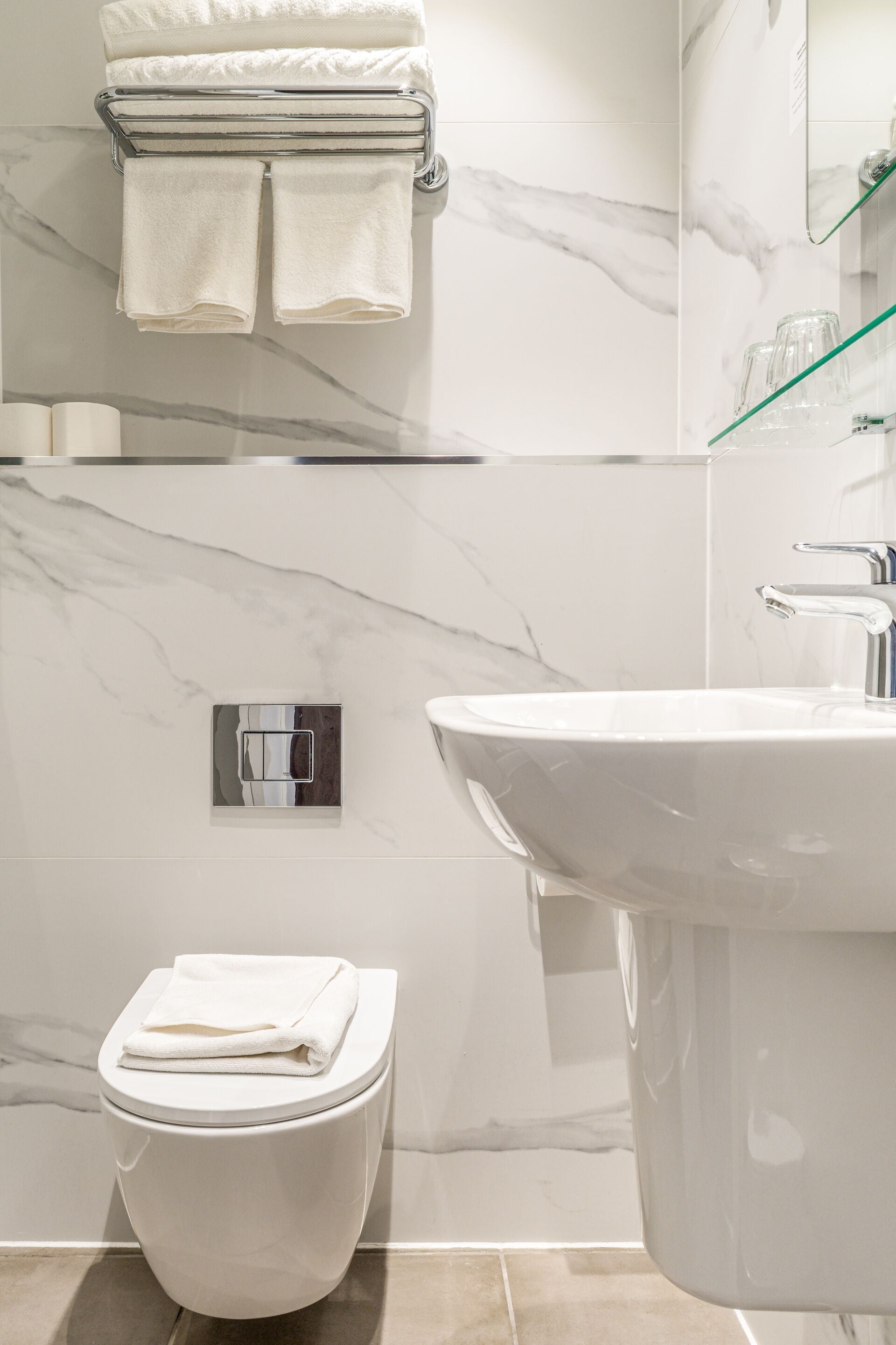 Ein modernes Badezimmer mit Toilette, Waschbecken und einer Marmor-Spritzschutzwand.