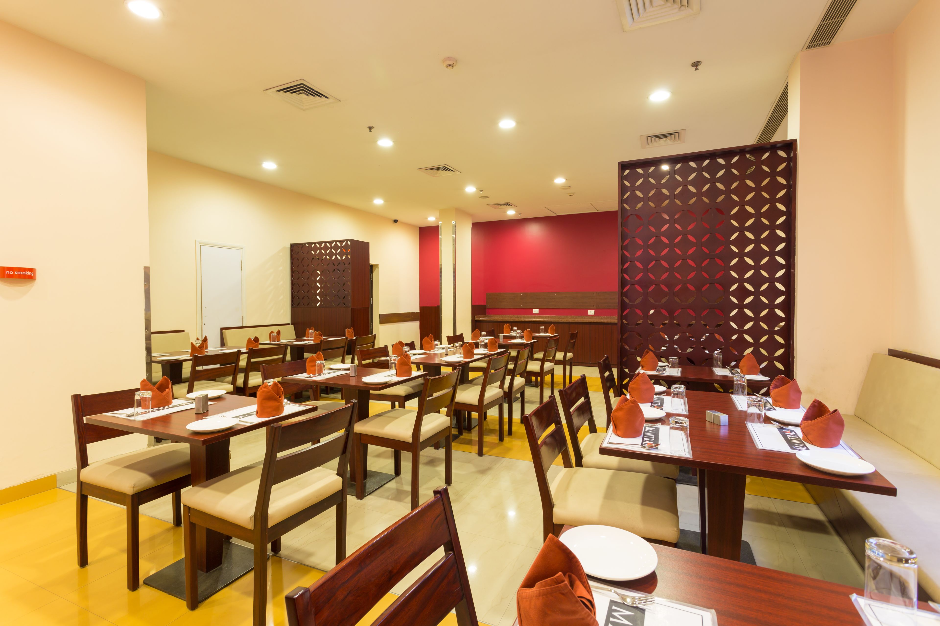 A restaurant with multiple tables and chairs, a counter, and a decorative partition.