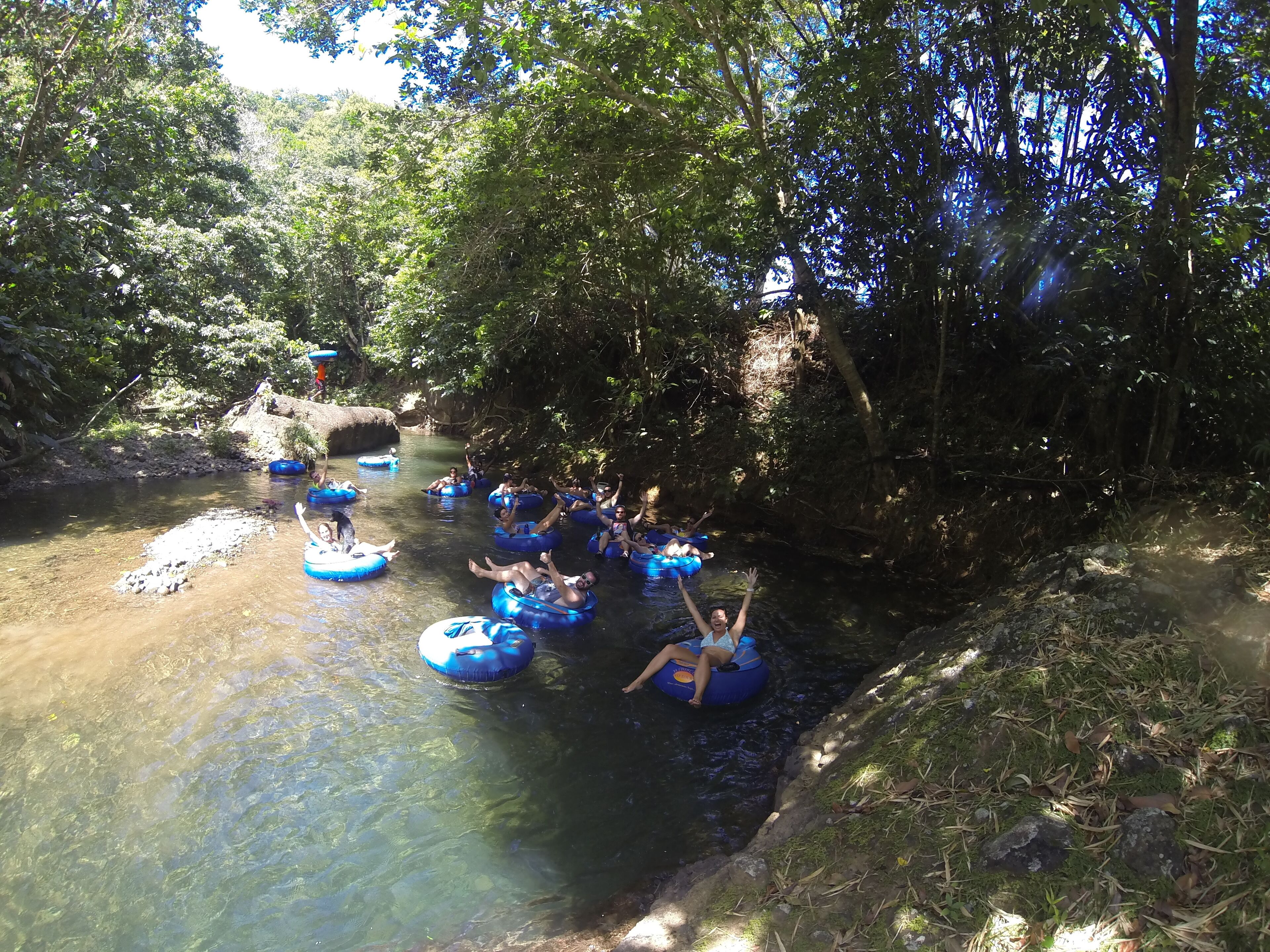 Personas flotando en balsas azules en un río rodeado de árboles.