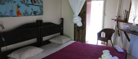 A bedroom with a bed, a mosquito net, a chair, and a shelf with items.