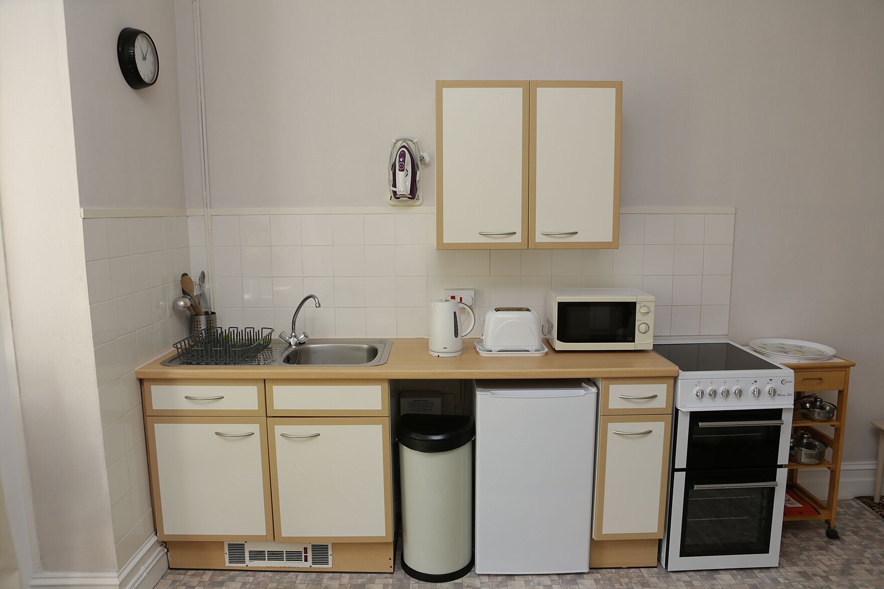 Een kleine keuken met een spoelbak, magnetron, broodrooster en een klein oven.