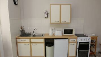 A compact kitchen with a sink, microwave, toaster, and small oven.