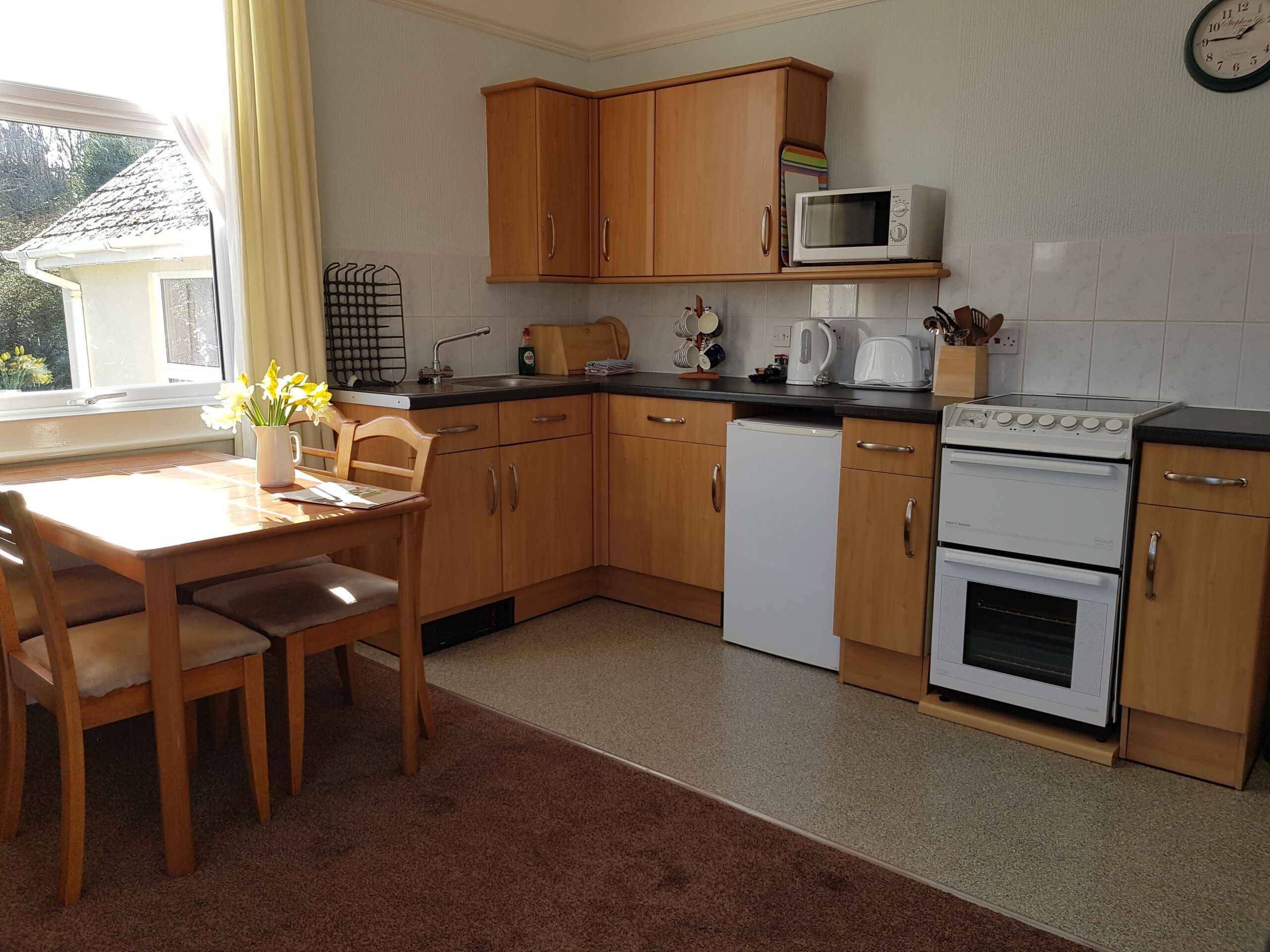 A kitchen with wooden cabinets, a microwave, a kettle, a toaster, and a dishwasher.