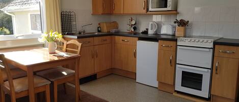A kitchen with wooden cabinets, a microwave, a kettle, a toaster, and a dishwasher.