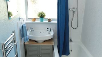 A bathroom with a white bathtub, a sink, and a shower.