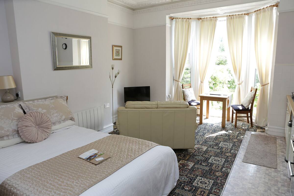 Una habitación de hotel con cama, sofá, televisión, mesa y silla.