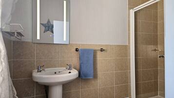 A bathroom with a sink, mirror, and shower.