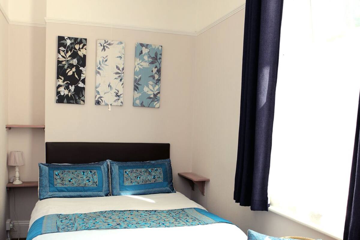 Un dormitorio con una cama, una silla y tres cuadros con motivos florales.