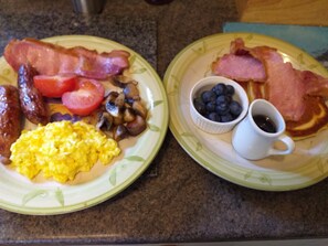 Two plates of breakfast food including bacon, sausages, scrambled eggs, tomatoes, mushrooms, blueberries, and a cup of coffee. - Broome Park Farm B&B (Kidderminster)