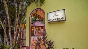 A reception area with a sign, a covered entrance, and tropical plants. - Indra Inn (Cabo Velas)