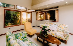 A room with a sofa, armchair, and a coffee table with a vase of flowers. - Hotel Heliconia (Monteverde)