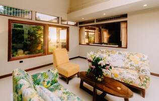 Una habitación con sofá, sillón y una mesa de centro con un jarrón de flores.