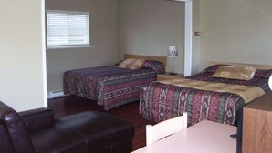 A bedroom with two beds, a desk, a chair, and a window with blinds. - Beach Grove Motel (Delta)