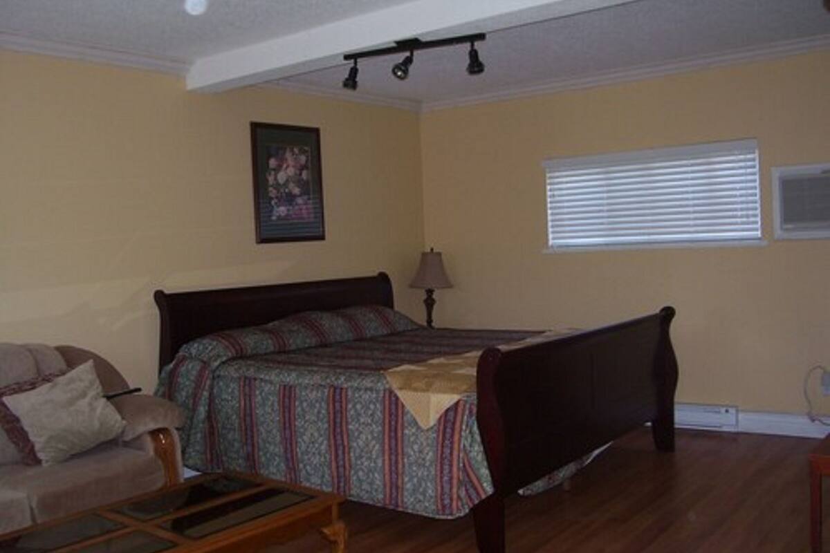 Un dormitorio con una cama, una silla, una lámpara y una ventana con persianas.