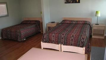 A room with two single beds, a small table, and a nightstand with a lamp.